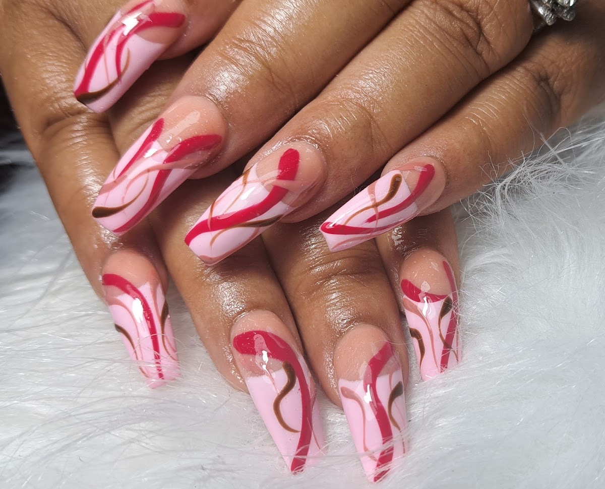 Pink and red hand-painted swirl nail art on long coffin nails at Da Nailz Boss in Decatur, GA